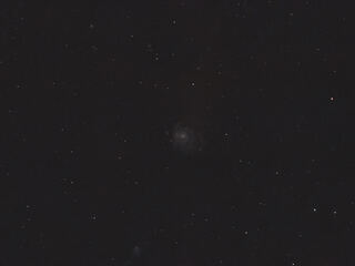 Messier 101 as a faint spiral galaxy in a wide star field